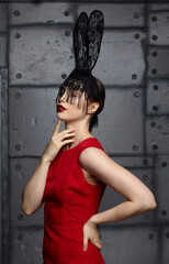 Young woman in black rabbit or hare fancy mask and red dress.