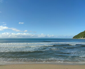 blue sea under blue clear sky with few white clouds far away