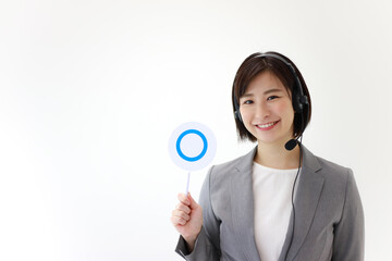 ヘッドセットを着け〇札を持つ女性社員