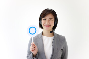 ヘッドセットを着け〇札を持つ女性社員