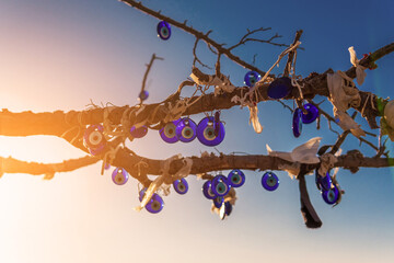 Evil eye beads, Dozens of evil eye beads tied to a tree branch, Turkish culture and the talisman of hiding from bad energy, blue sky and blue evil eye beads.