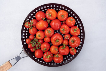 Freshly picked cherry tomatoes in a leaky frying pizza griddle pan with holes to cook vegetables...