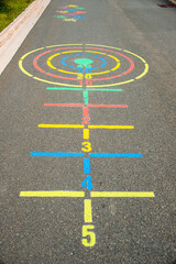 A colorful outdoor children's recreation game that has multiple lines and circles painted on...