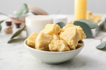 Bowl with cocoa butter on light background
