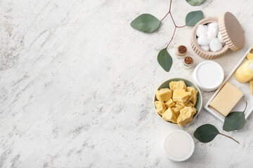 Bowl with cocoa butter and bath supplies on light background