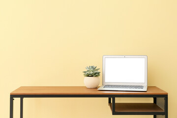 Stylish workplace with modern laptop near light wall