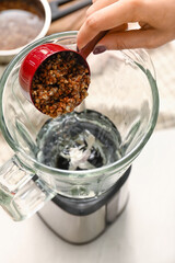 Woman preparing tasty buckwheat milk on kitchen table, closeup