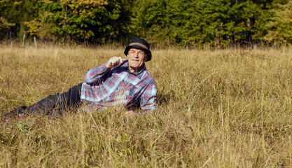 Naklejka na ściany i meble the senior man rests lying on a meadow in nature