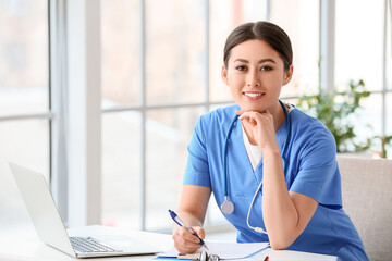 Female Asian doctor sitting at table in clinic