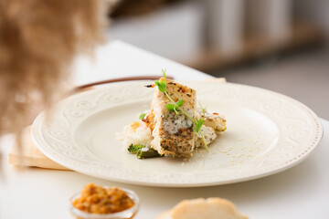 Plate with tasty baked cod fillet, rice and vegetables on table in restaurant