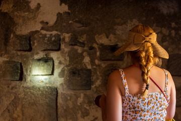 Young woman explorer exploring an old underground city, young woman exploring wall carvings, Travel to Turkey
