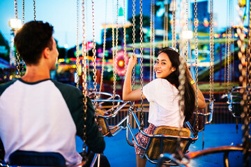 Young couple riding the swings at an amusement park