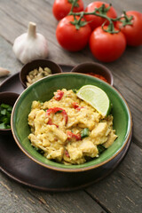 Bowl of tasty chicken curry on wooden background
