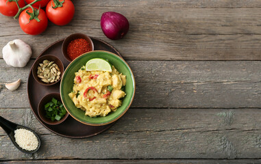 Bowl of tasty chicken curry and ingredients on wooden background