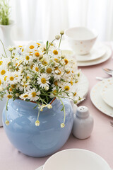 Stylish table setting and chamomile flowers in dining room