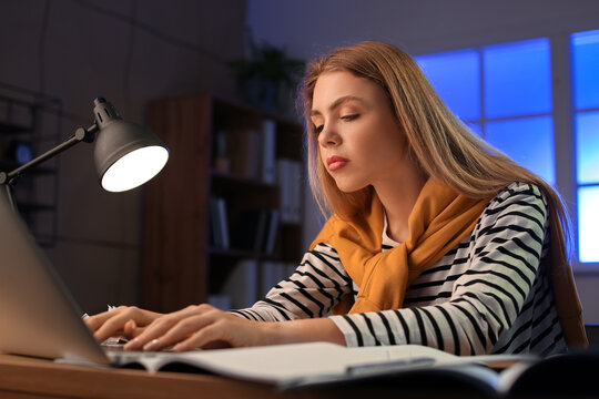 Female student preparing for exam at home late in evening - Powered by Adobe