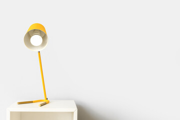 Modern lamp on table near white wall
