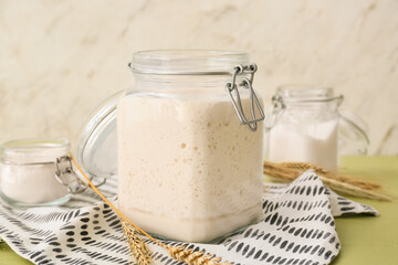 Open jar with fresh sourdough and spikelets on table