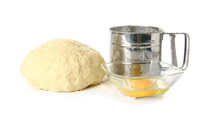 Fresh dough, flour sieve mug and bowl with egg on white background