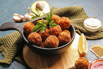 Frying pan with tasty cod cutlets on dark background, closeup