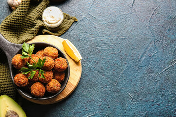 Frying pan with tasty cod cutlets and sauce on dark background
