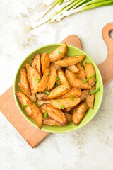 Bowl of tasty baked potato with green onion on light background