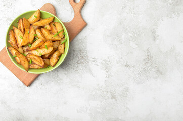 Bowl of tasty baked potato with green onion on light background