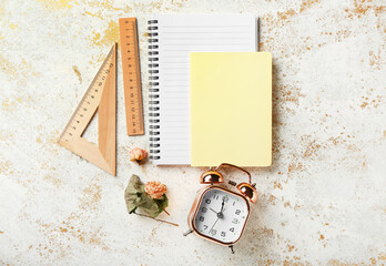 Set of stationery supplies and alarm clock on color background