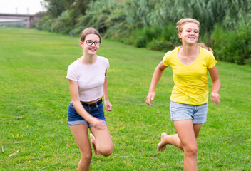 Laughing girlfriends are jogging together in the park and having fun