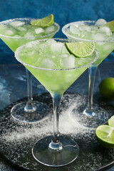 Slate plate with glasses of tasty daiquiri cocktail on color background, closeup