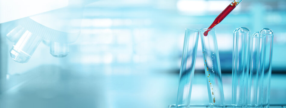 orange drop in glass test tube and microscope in blue light medical science laboratory banner background