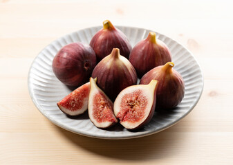 Figs and cut figs on a plate on the table.