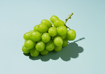 Shine Muscat grapes with water droplets on a green background.