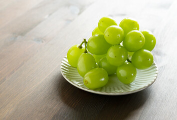 Shine Muscat grapes served on a plate set against a wooden background.