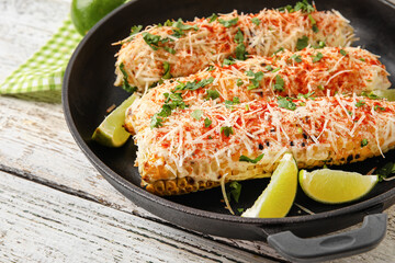 Frying pan with tasty Elote Mexican Street Corn on white wooden background, closeup