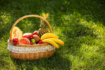 Fototapeta na wymiar Wicker basket with fresh fruits on grass