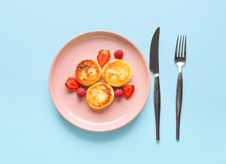 Plate with delicious cottage cheese pancakes and berries on color background
