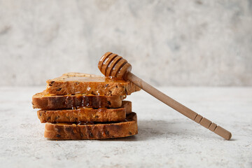 Tasty toasted bread with honey and dipper on light background