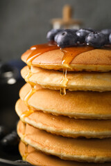 Tasty pancakes with honey and berries on table, closeup