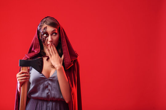 Surprised woman with Halloween makeup and axe on color background