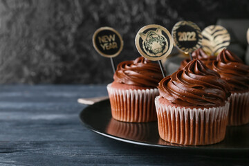 Plate with tasty cupcakes for New Year 2022 celebration on table