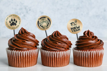 Tasty cupcakes for New Year 2022 celebration on grunge background