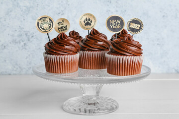 Dessert stand with tasty cupcakes for New Year 2022 celebration on table