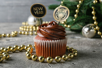Tasty cupcake for New Year 2022 celebration with decor on grunge background