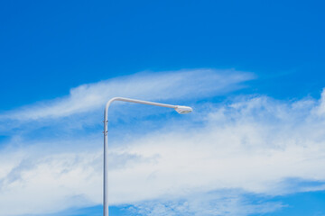 The street light pole stand against the bright blue sky background with copy space