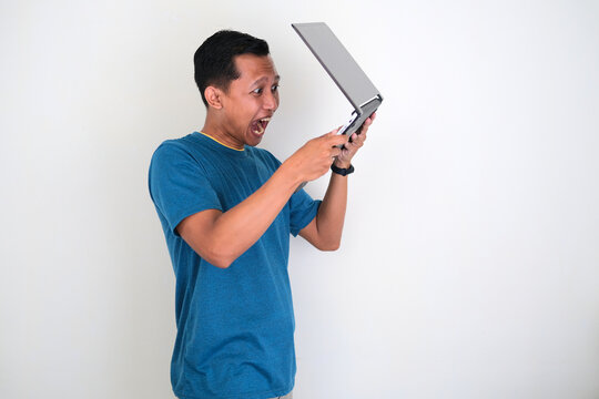 Asian young man with angry expression and throw a laptop isolated on white background.