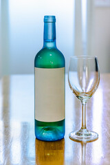 White wine bottele and glass on blurred window background