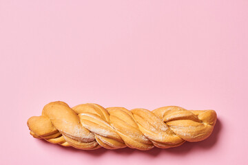 Fresh braided bread isolated on pink background with copy space. Horizontal photo.