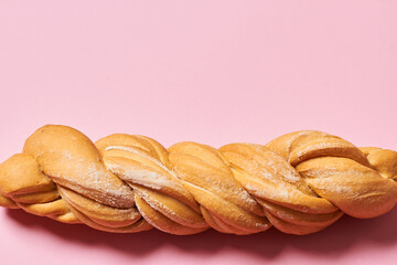 Fresh braided bread isolated on pink background with copy space. Horizontal photo.