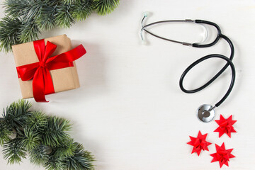 Celebrating Christmas in health care. Flat lay top view. Stethoscope, fir branches with ornaments on a white background. Top view, flat lay.